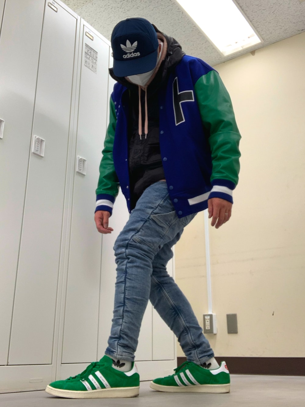 ブルー系のスタジャン、ブラック系のマウンテンパーカー、ブルー系のデニムパンツを着用したメンズの春コーディネートの2枚目の写真