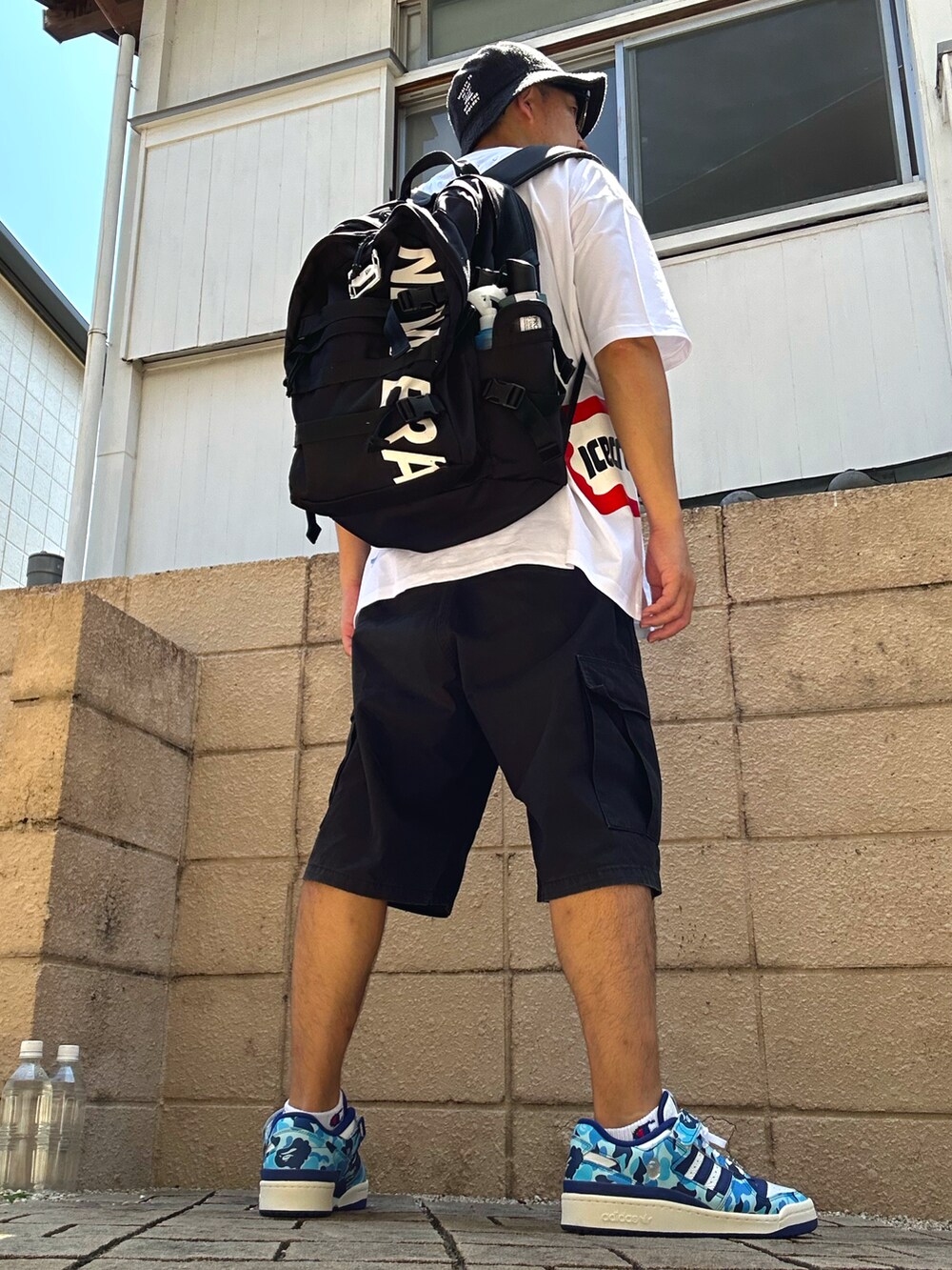 ブラック系のカーゴパンツ、ブルー系のスニーカー、ホワイト系のTシャツ/カットソーを着用したメンズの夏コーディネートの3枚目の写真