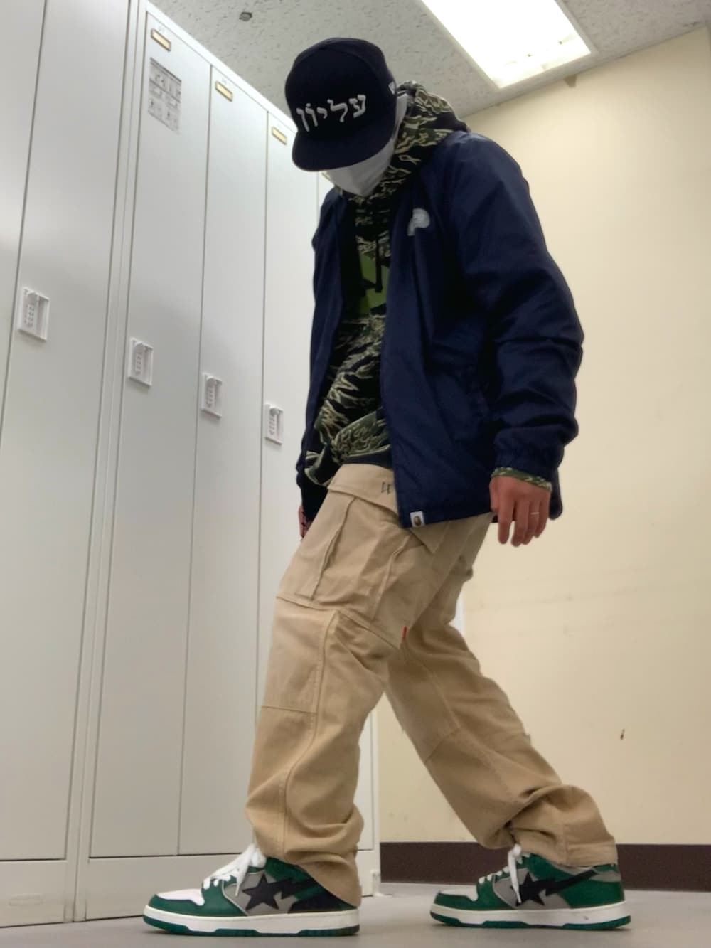 ブルー系のナイロンジャケット、グリーン系のパーカー、ベージュ系のカーゴパンツを着用したメンズの春コーディネートの2枚目の写真