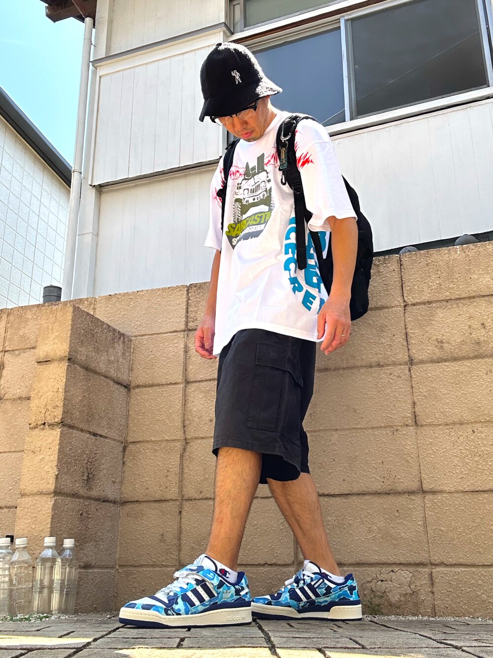 ブラック系のカーゴパンツ、ブルー系のスニーカー、ホワイト系のTシャツ/カットソーを着用したメンズの夏コーディネートの2枚目の写真