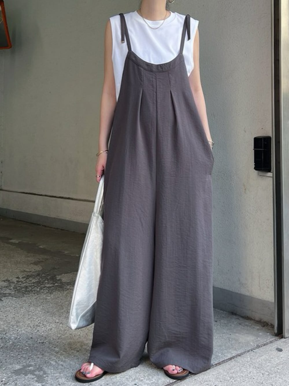 シルバー系のショルダーバッグ、ブラック系のサロペット/オーバーオール、ホワイト系のトップスを着用したレディースの夏コーディネートの2枚目の写真