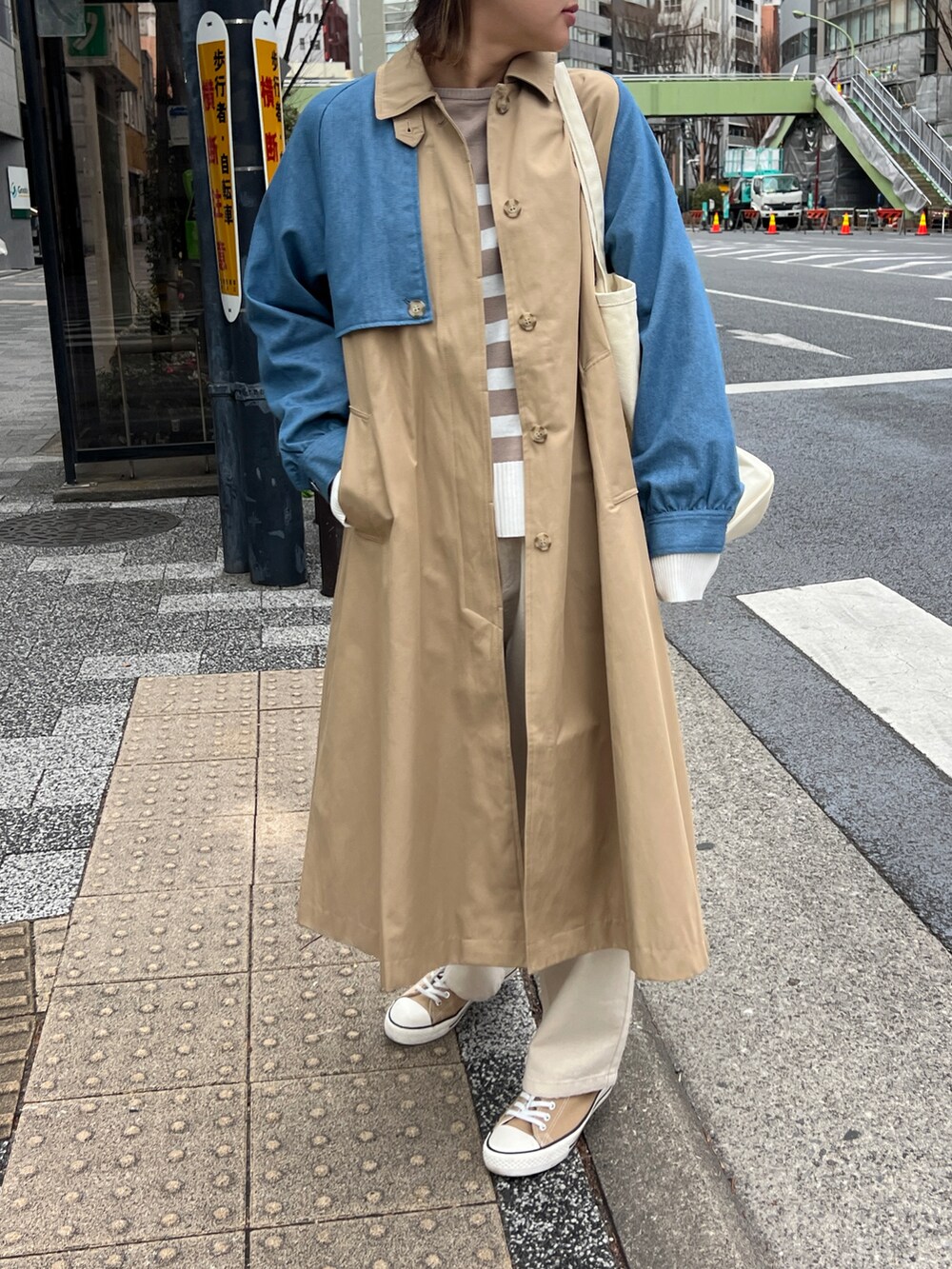 ベージュ系のステンカラーコートを着用したレディースの春コーディネートの2枚目の写真