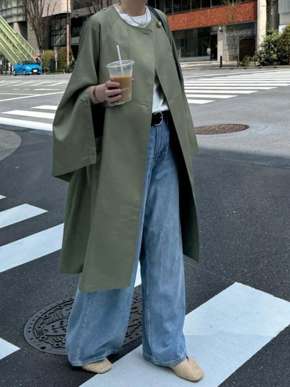 ベージュ系のノーカラーコート、ブルー系のデニムパンツを着用したレディースの春コーディネートの2枚目の写真