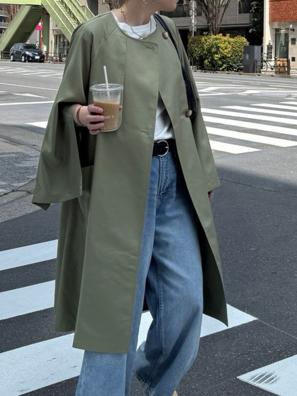 ベージュ系のノーカラーコート、ブルー系のデニムパンツを着用したレディースの春コーディネートの3枚目の写真