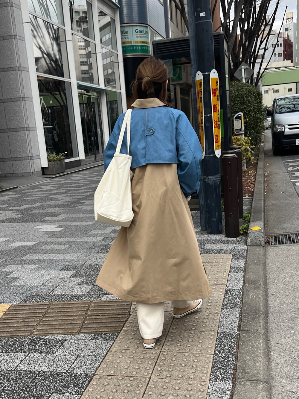ベージュ系のステンカラーコートを着用したレディースの春コーディネートの3枚目の写真