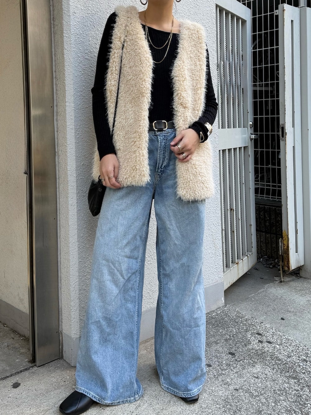 グレー系のベスト、ブラック系のスカート、ブラック系のニット/セーターを着用したレディースの秋コーディネートの2枚目の写真