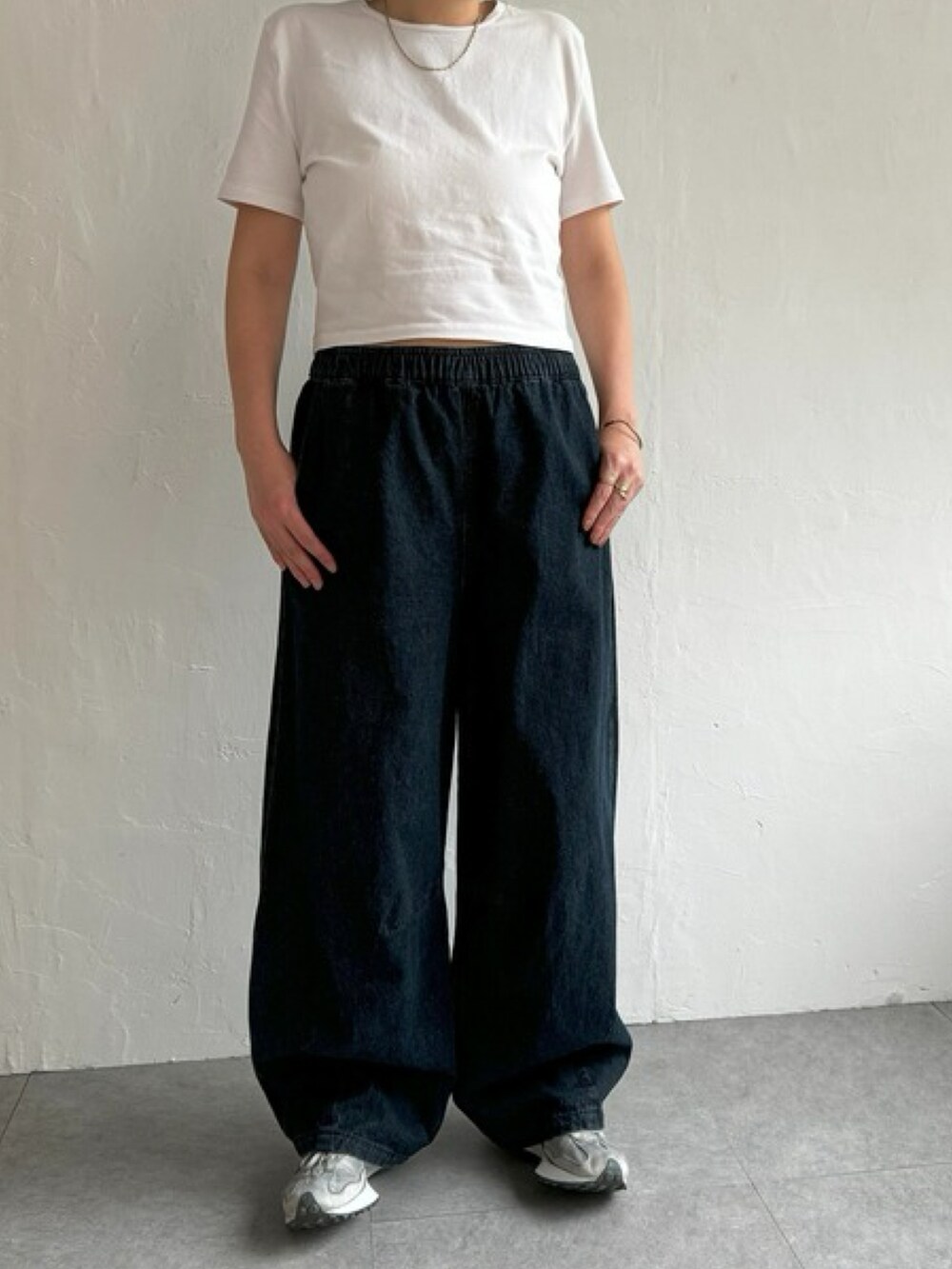 ホワイト系のトップス、ブルー系のデニムパンツ、グレー系のスニーカーを着用したレディースの夏コーディネートの3枚目の写真