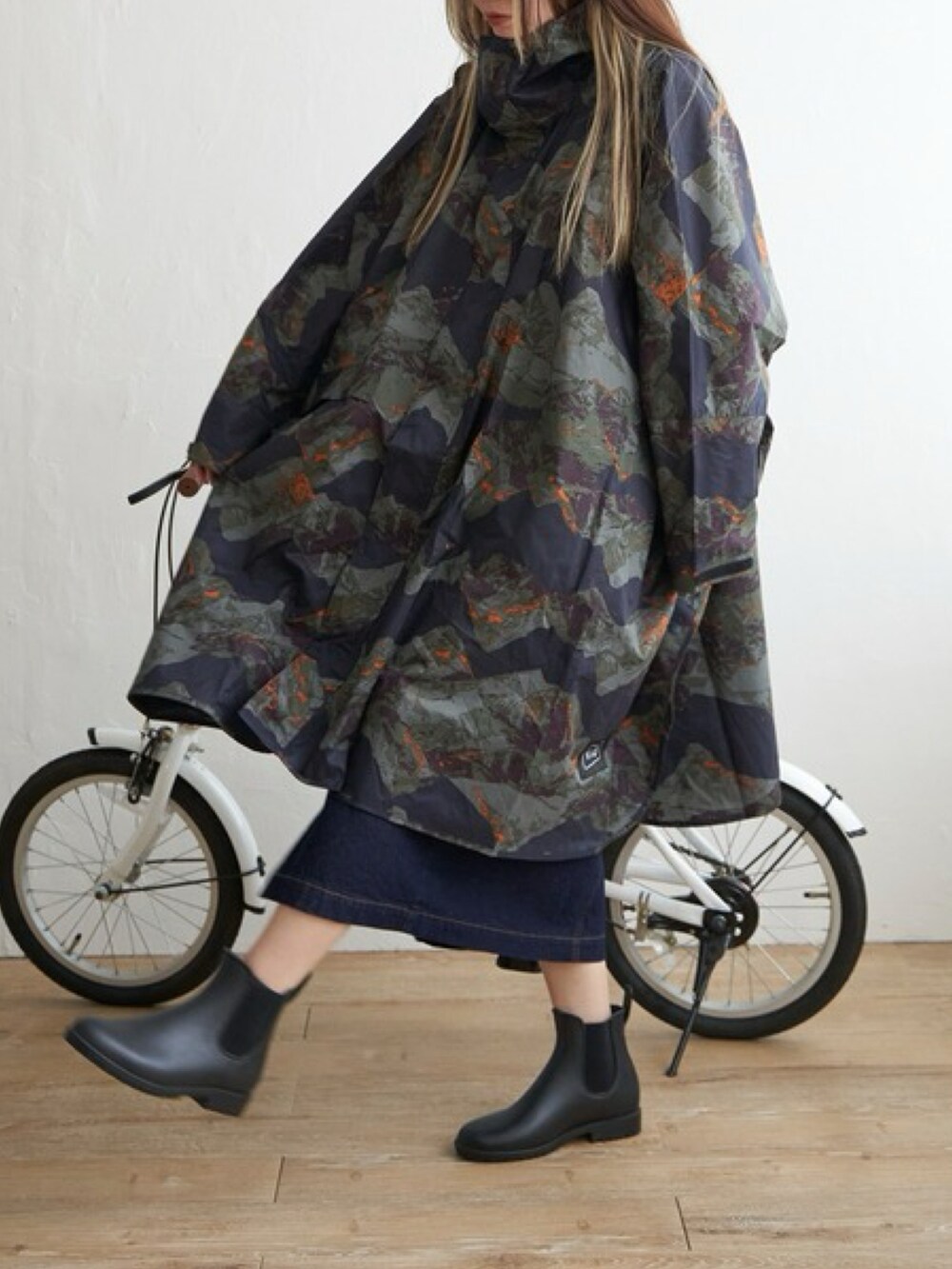 ブルー系のスカート、ブラック系のレインシューズ、グリーン系のレインコート/ポンチョを着用したレディースの春コーディネートの2枚目の写真
