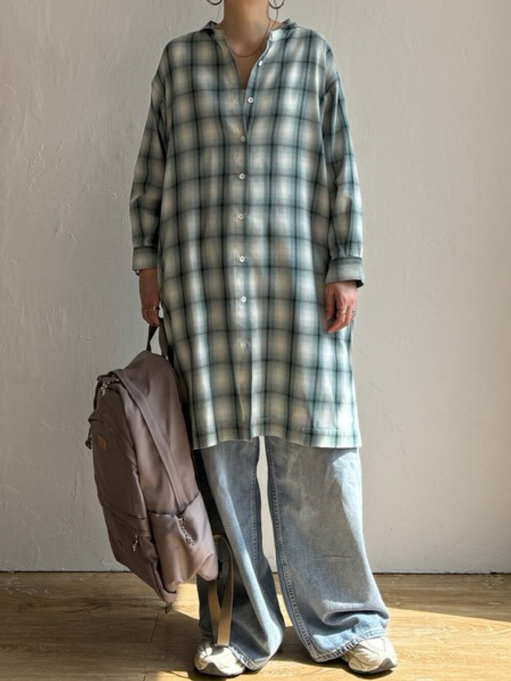 オレンジ系のワンピース、ホワイト系のスニーカー、ベージュ系のバックパック/リュックを着用したレディースの春コーディネートの2枚目の写真