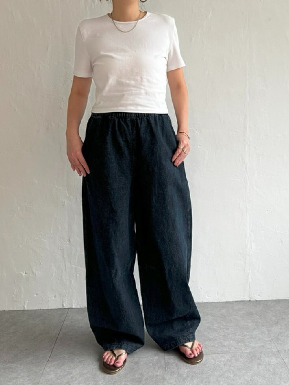 ホワイト系のトップス、ブルー系のデニムパンツ、グレー系のスニーカーを着用したレディースの夏コーディネートの2枚目の写真