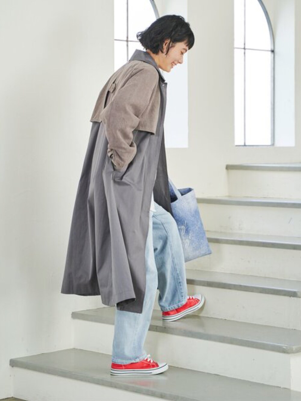 グレー系のステンカラーコート、オレンジ系のトートバッグ、ホワイト系のTシャツ/カットソーを着用したレディースの春コーディネートの2枚目の写真