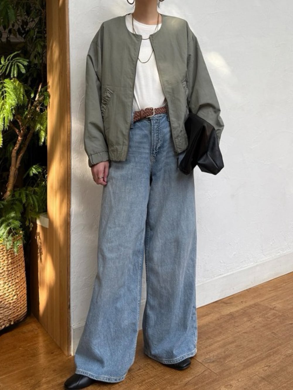 グリーン系のブルゾン、ブルー系のデニムパンツ、ホワイト系のトップスを着用したレディースの冬コーディネートの2枚目の写真