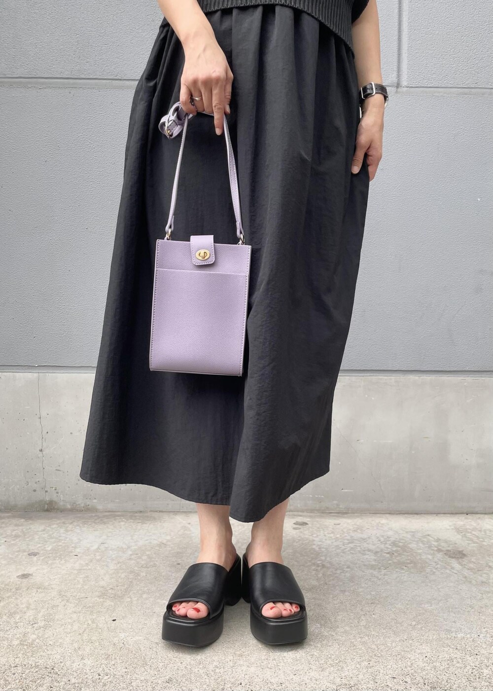 パープル系のショルダーバッグ、ブラック系のサンダル、ブラック系のワンピースを着用したレディースの夏コーディネートの4枚目の写真