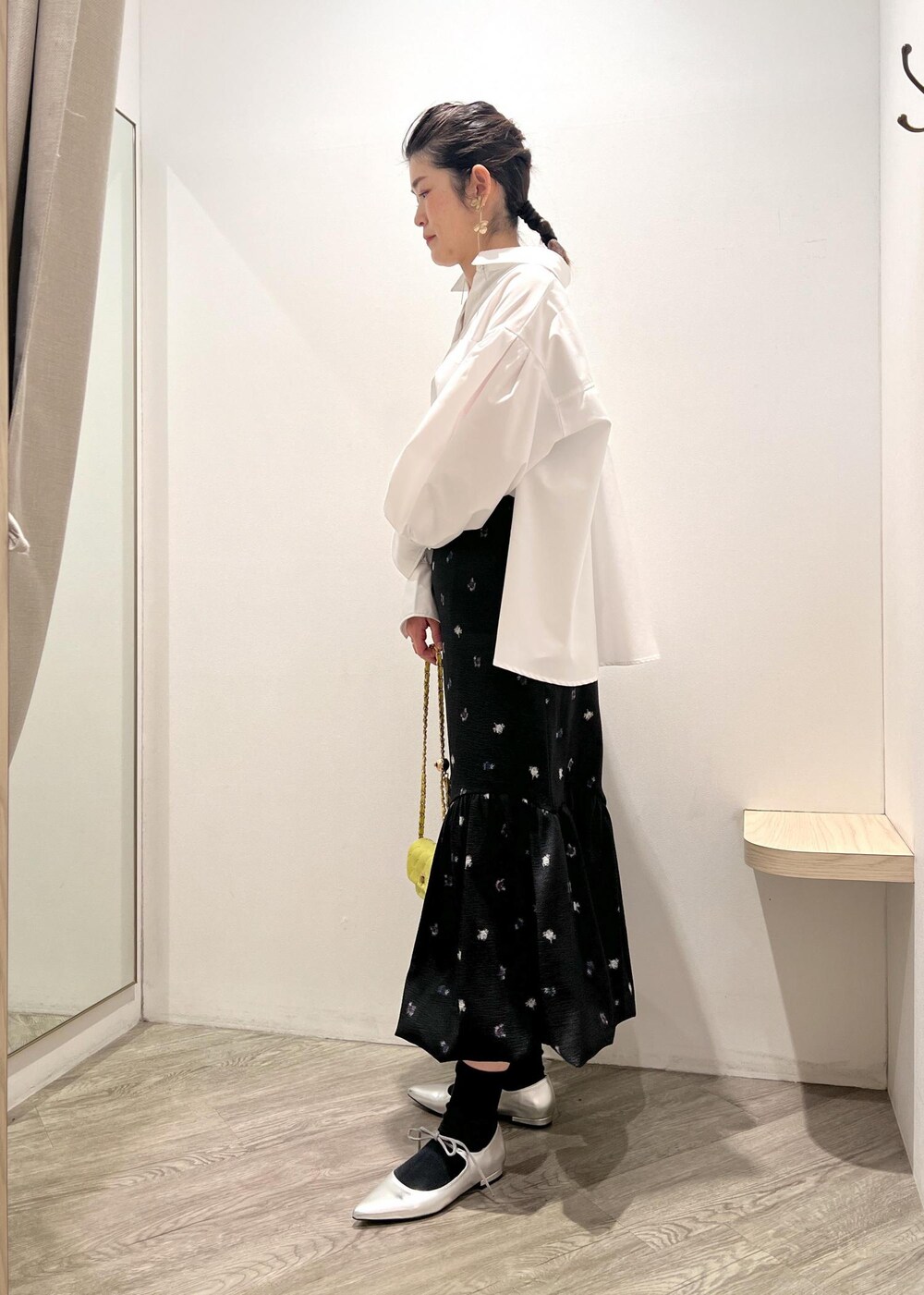 シルバー系のパンプス、イエロー系のショルダーバッグ、ブラック系のスカートを着用したレディースの冬コーディネートの2枚目の写真