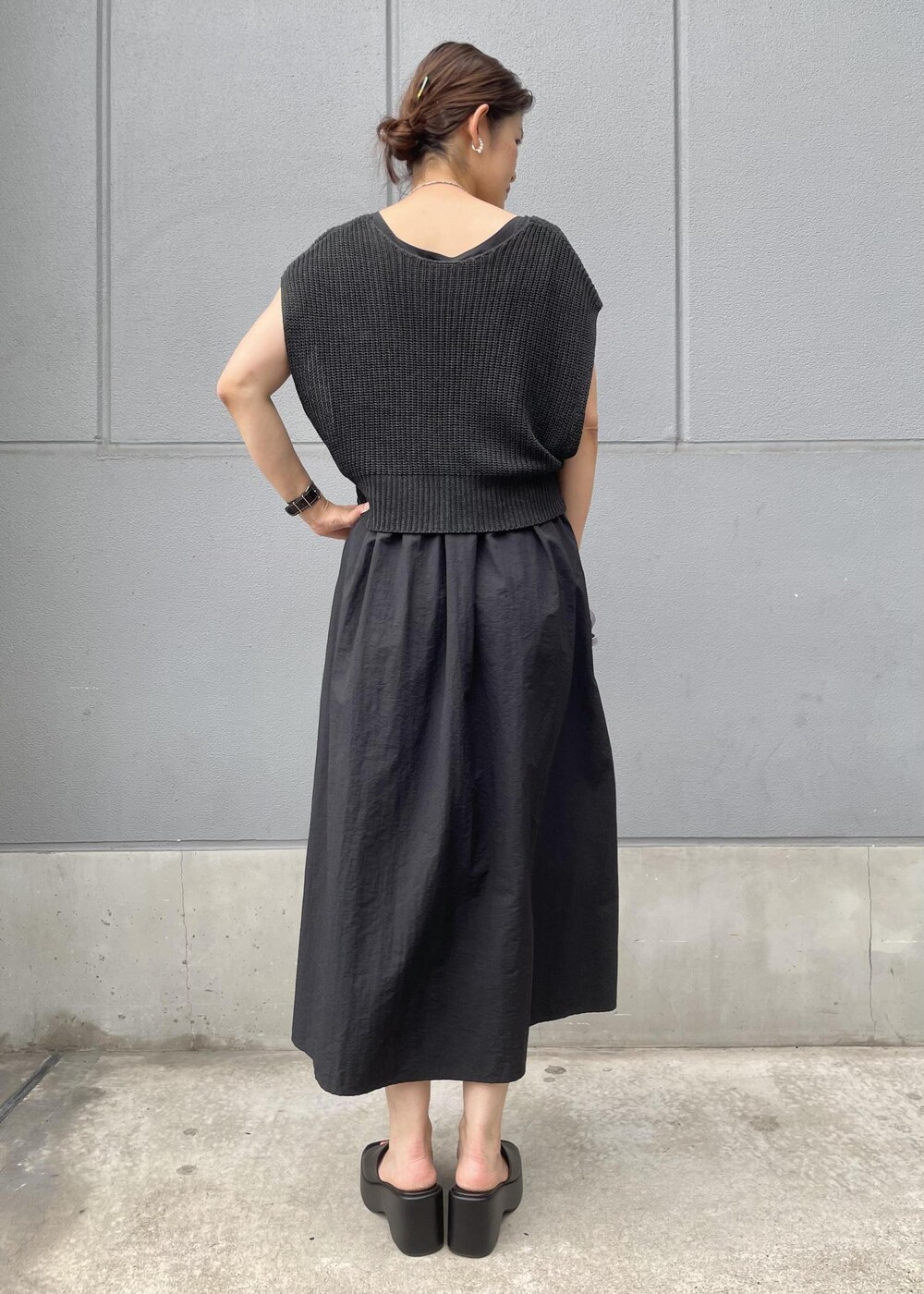 パープル系のショルダーバッグ、ブラック系のサンダル、ブラック系のワンピースを着用したレディースの夏コーディネートの2枚目の写真