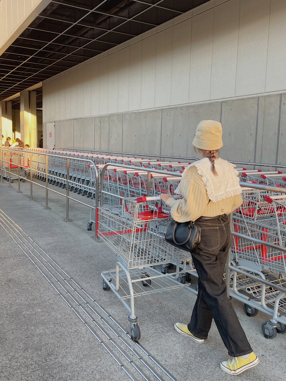 ベージュ系のニット/セーター、ブラック系のボストンバッグ、ブラック系のデニムパンツを着用したレディースの秋コーディネートの2枚目の写真