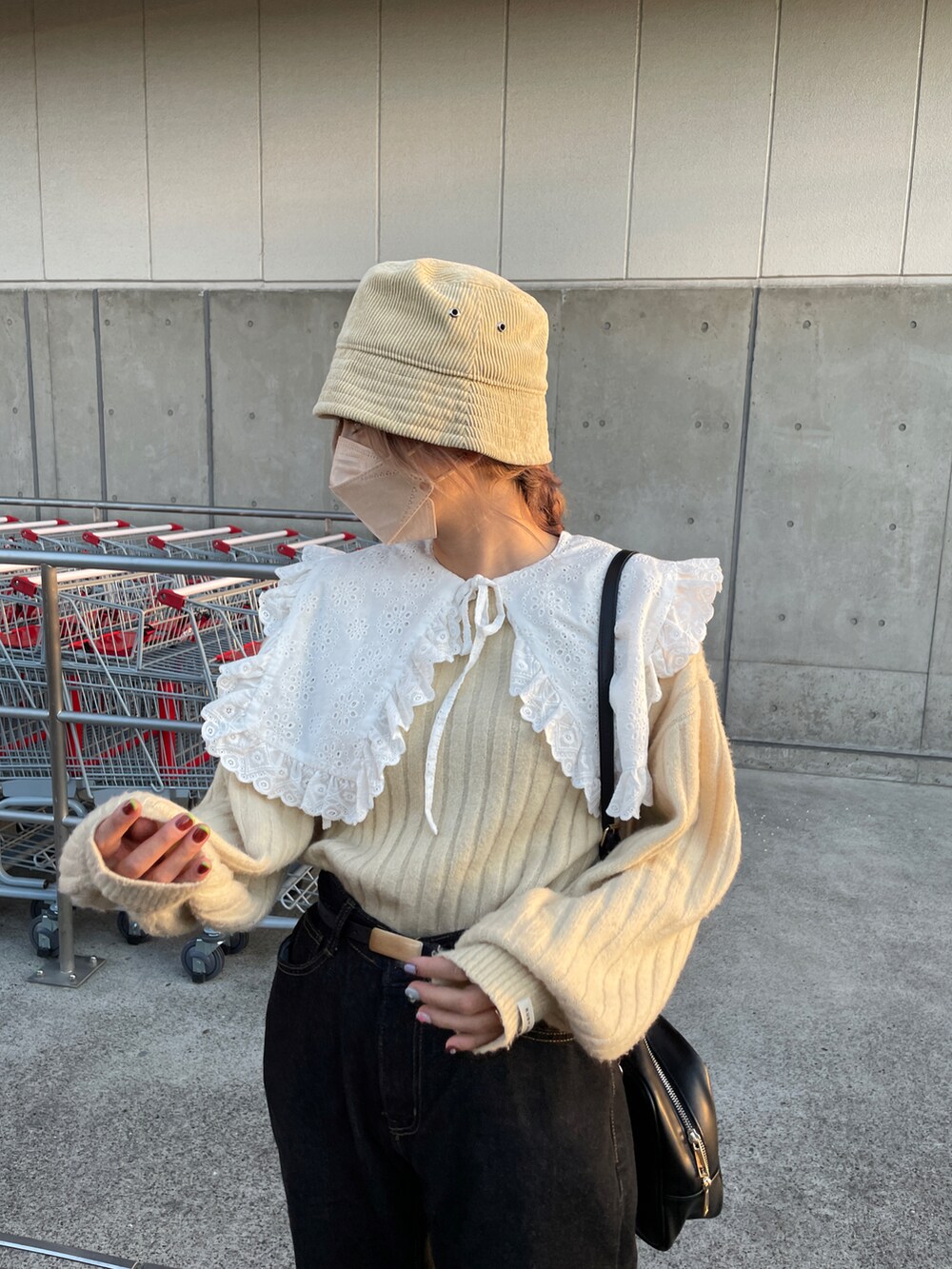 ベージュ系のニット/セーター、ブラック系のボストンバッグ、ブラック系のデニムパンツを着用したレディースの秋コーディネートの3枚目の写真