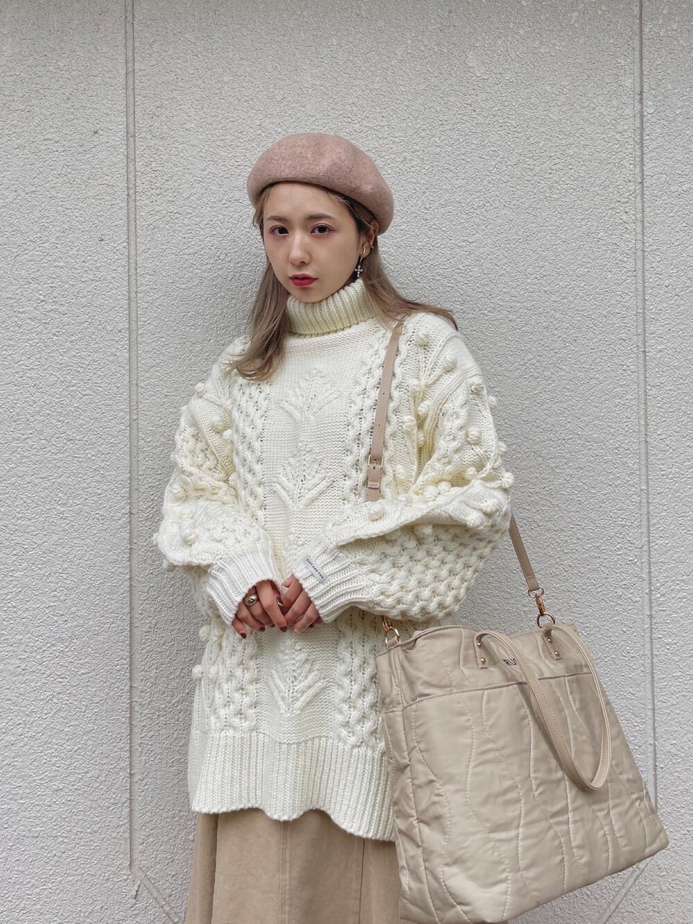 ホワイト系のニット/セーター、ベージュ系のバッグ、ベージュ系のスカートを着用したレディースの冬コーディネートの3枚目の写真