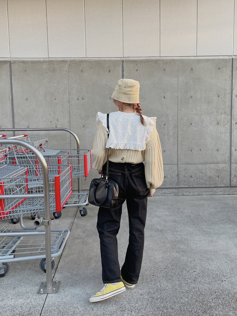 ベージュ系のニット/セーター、ブラック系のボストンバッグ、ブラック系のデニムパンツを着用したレディースの秋コーディネートの4枚目の写真