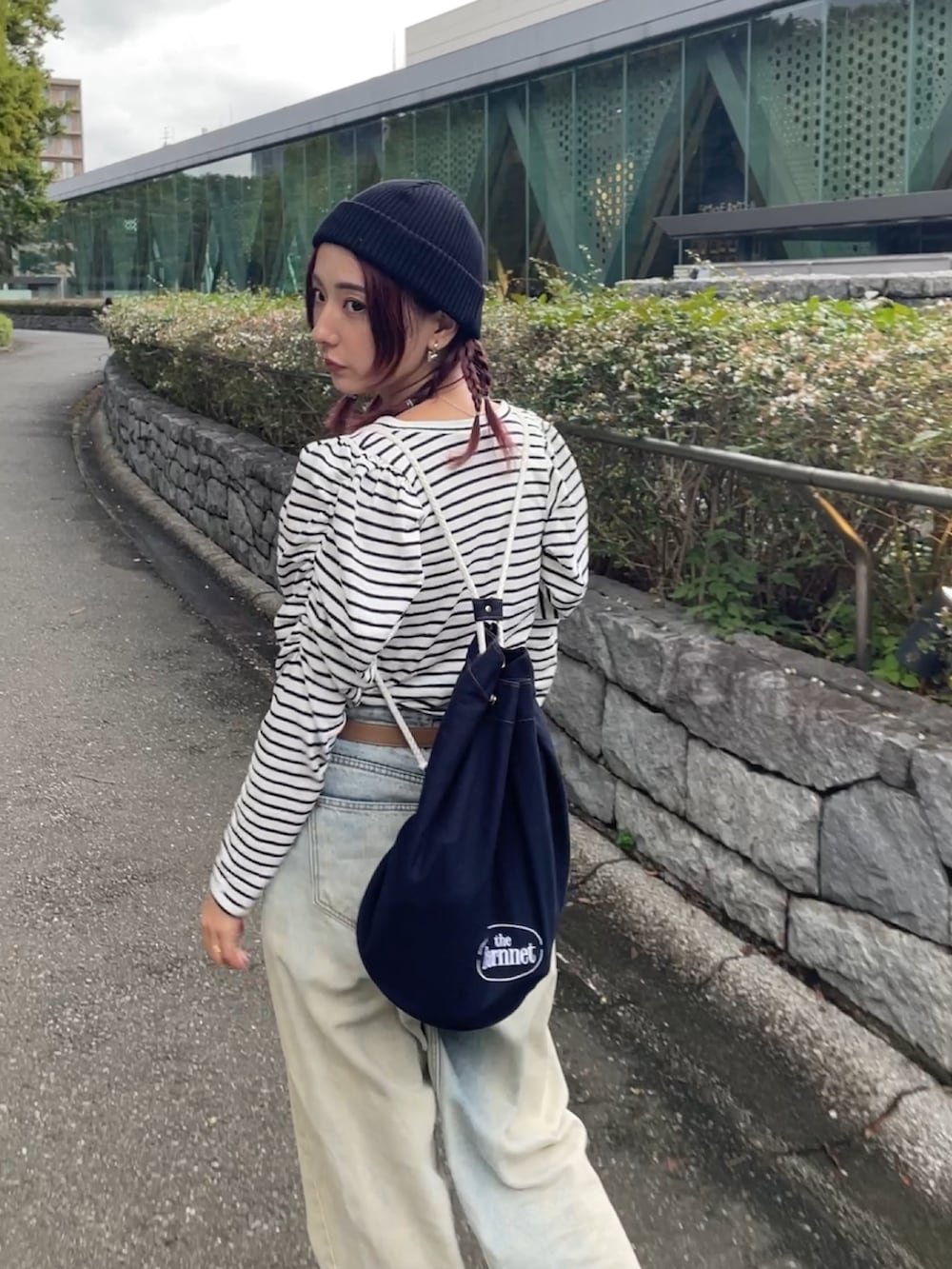ブルー系のデニムパンツ、ブラック系のスニーカー、ブルー系のショルダーバッグを着用したレディースの秋コーディネートの2枚目の写真