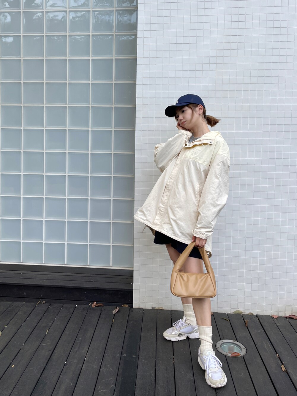 ホワイト系のナイロンジャケット、イエロー系のショルダーバッグ、ホワイト系のスニーカーを着用したレディースの春コーディネートの2枚目の写真