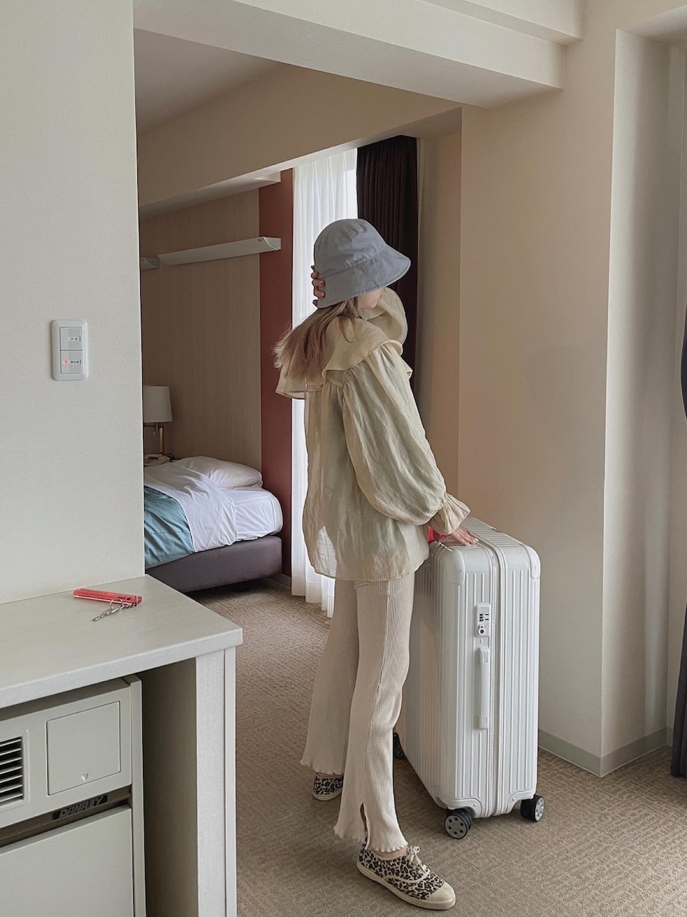 ベージュ系のシャツ/ブラウス、ベージュ系のスニーカー、ホワイト系のスーツケース/キャリーバッグを着用したレディースの春コーディネートの2枚目の写真