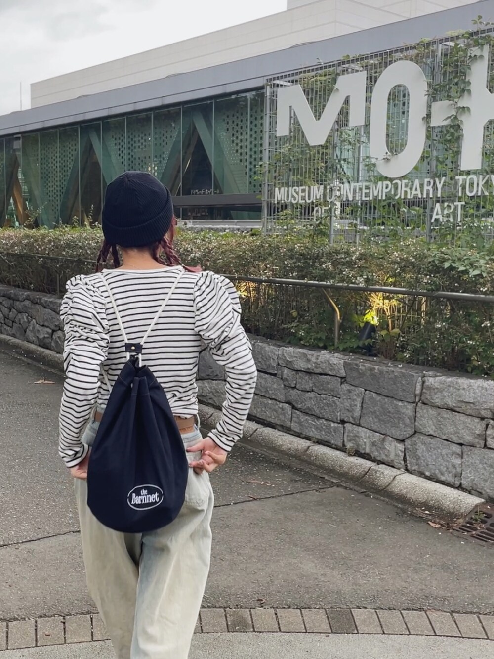 ブルー系のデニムパンツ、ブラック系のスニーカー、ブルー系のショルダーバッグを着用したレディースの秋コーディネートの3枚目の写真