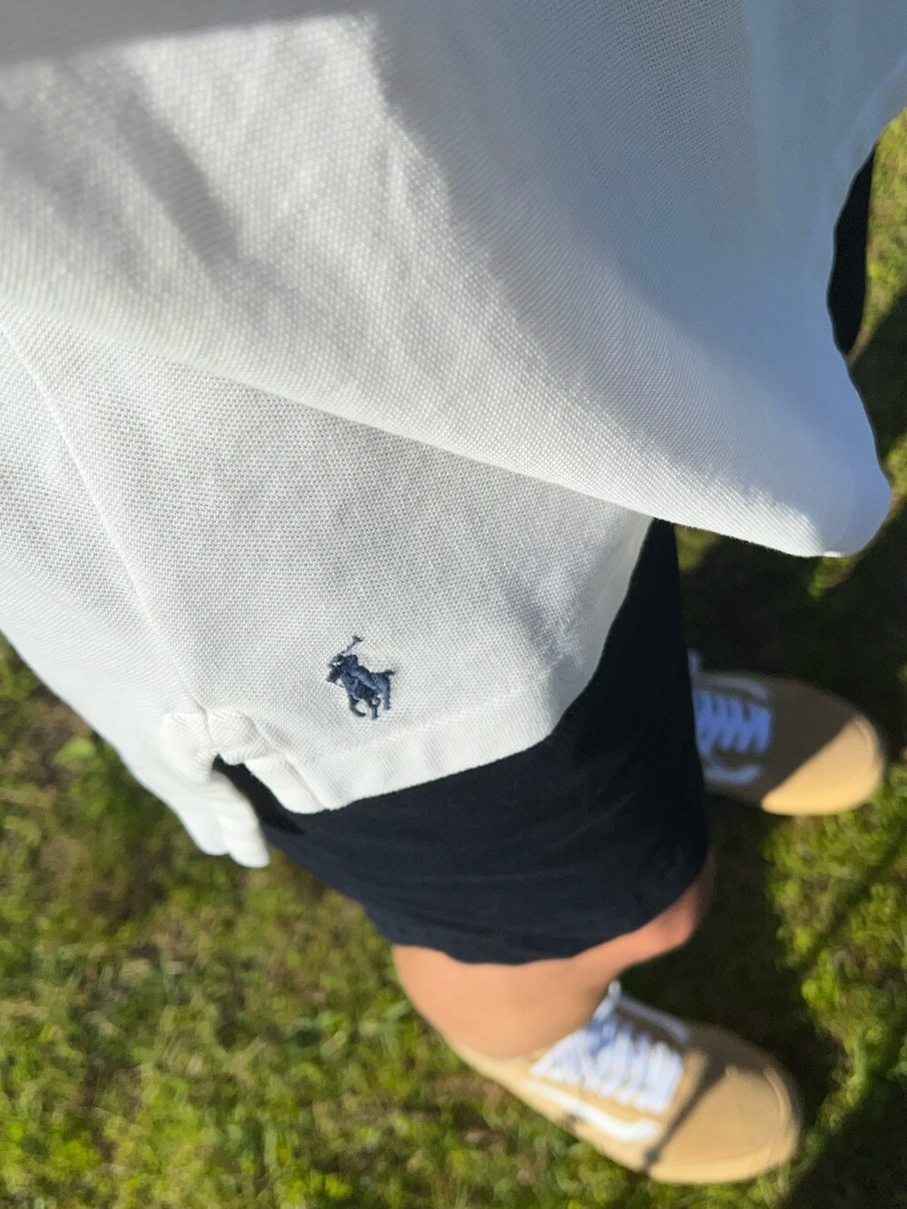 ホワイト系のポロシャツ、ブルー系のチノパンツ、ベージュ系のスニーカーを着用したメンズの夏コーディネートの3枚目の写真