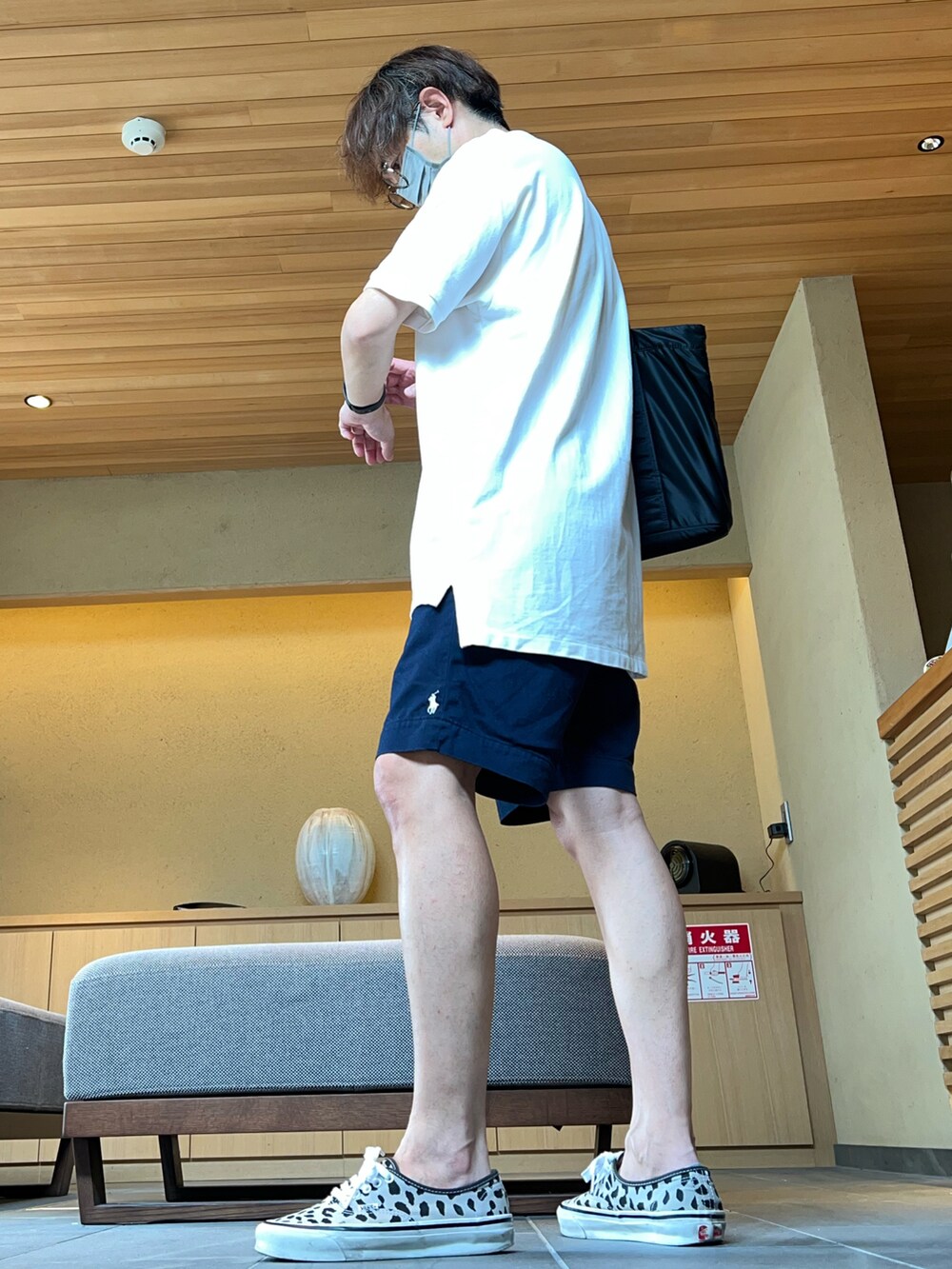 ブルー系のチノパンツ、ホワイト系のポロシャツ、ブラック系のトートバッグを着用したメンズの夏コーディネートの2枚目の写真