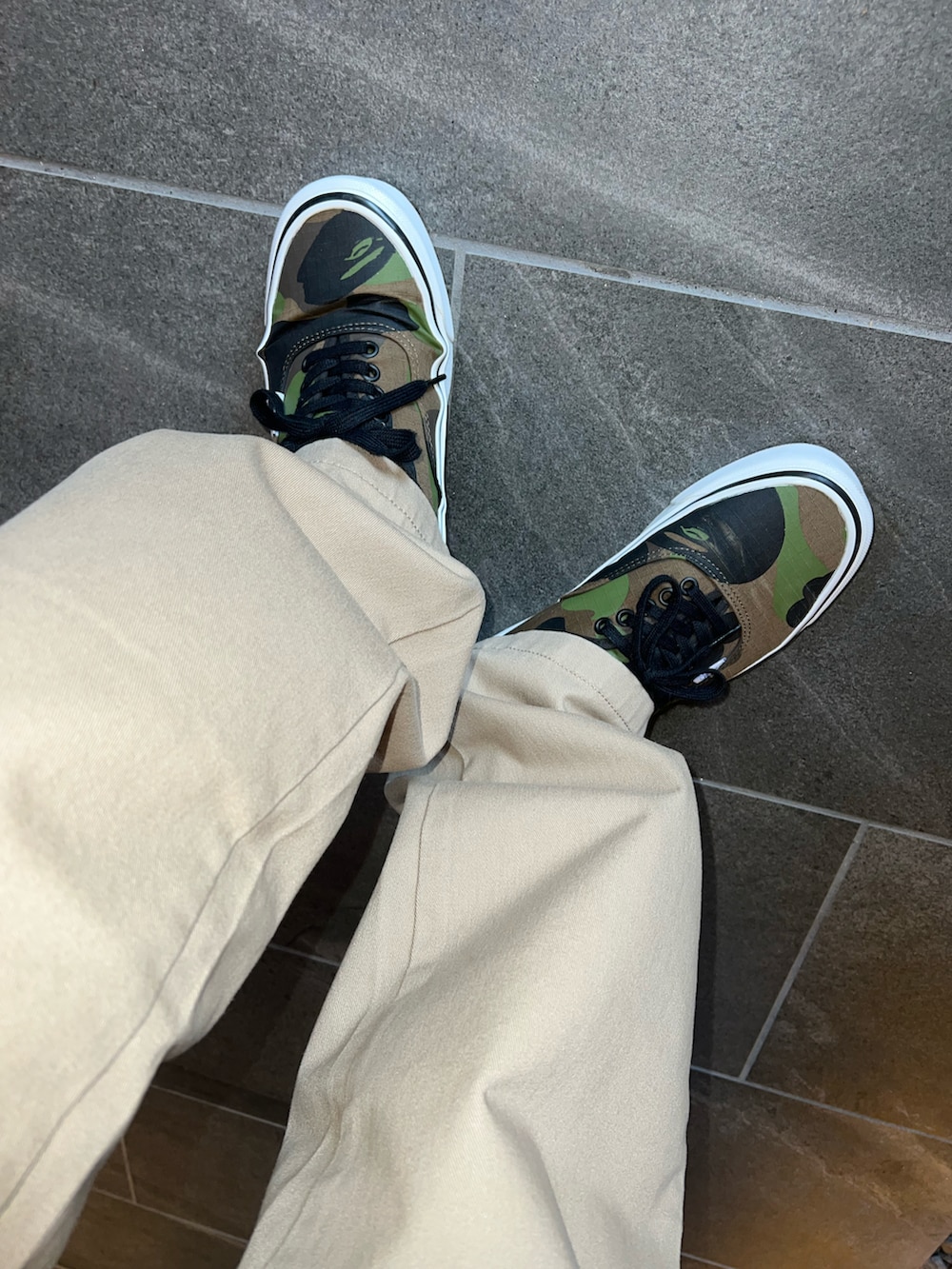 グリーン系のパーカー、ベージュ系のチノパンツ、グリーン系のスニーカーを着用したメンズの秋コーディネートの4枚目の写真