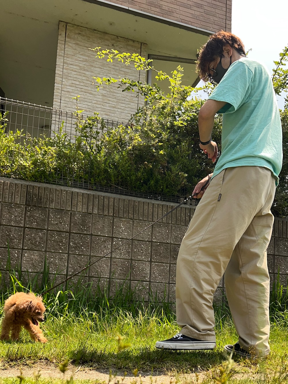 グリーン系のTシャツ/カットソー、ベージュ系のチノパンツ、ブラック系のスニーカーを着用したメンズの夏コーディネートの2枚目の写真