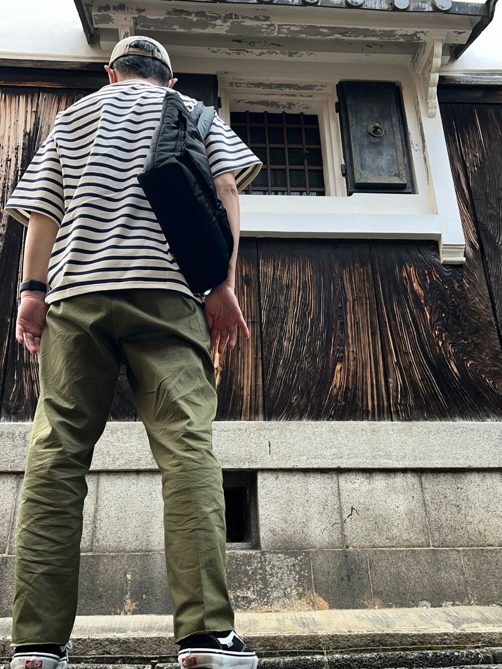 グリーン系のチノパンツ、ブラック系のスニーカー、ブルー系のTシャツ/カットソーを着用したメンズの春コーディネートの2枚目の写真