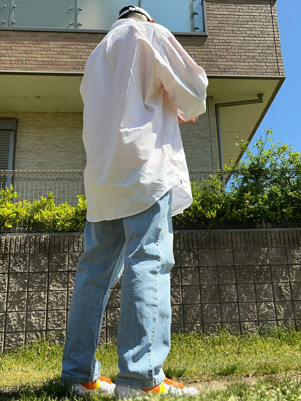 ブルー系のデニムパンツ、ホワイト系のシャツ/ブラウス、オレンジ系のTシャツ/カットソーを着用したメンズの春コーディネートの2枚目の写真