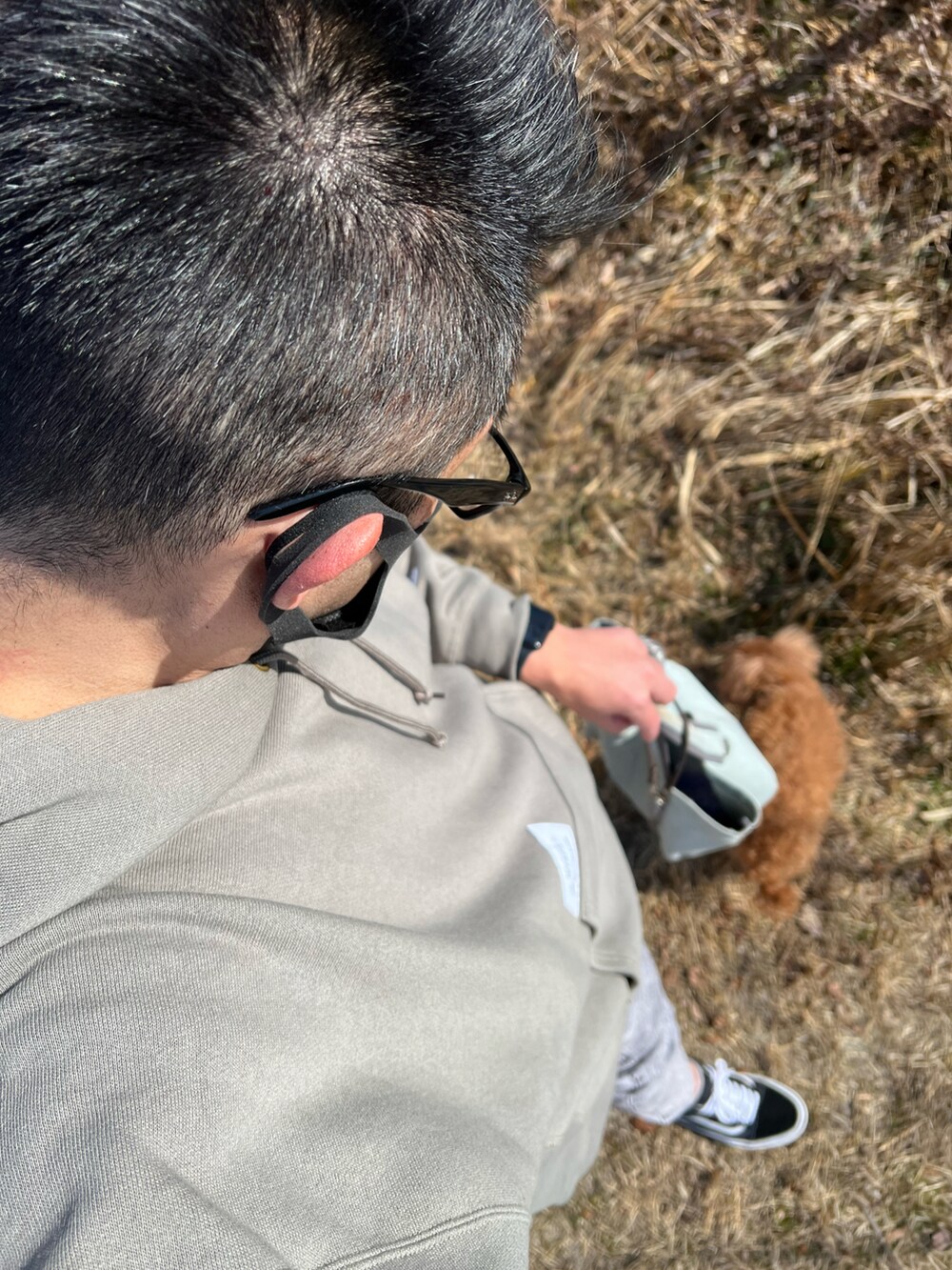 グレー系のデニムパンツ、ブラック系のスニーカー、グリーン系のパーカーを着用したメンズの冬コーディネートの2枚目の写真