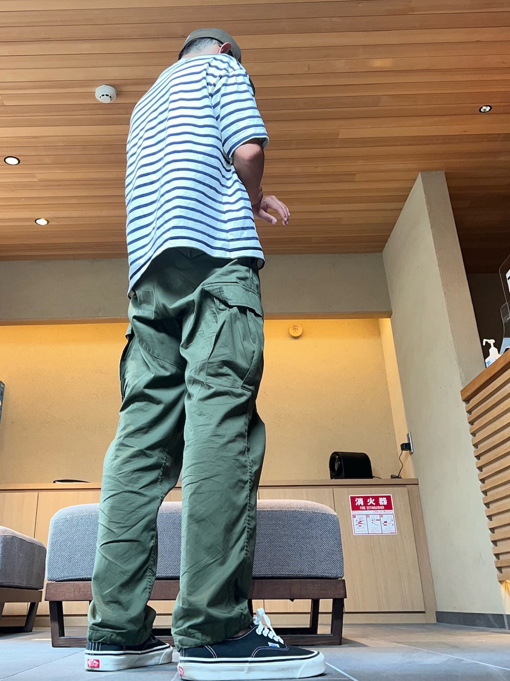 グリーン系のカーゴパンツ、ブルー系のTシャツ/カットソー、ブラック系のスニーカーを着用したメンズの秋コーディネートの2枚目の写真