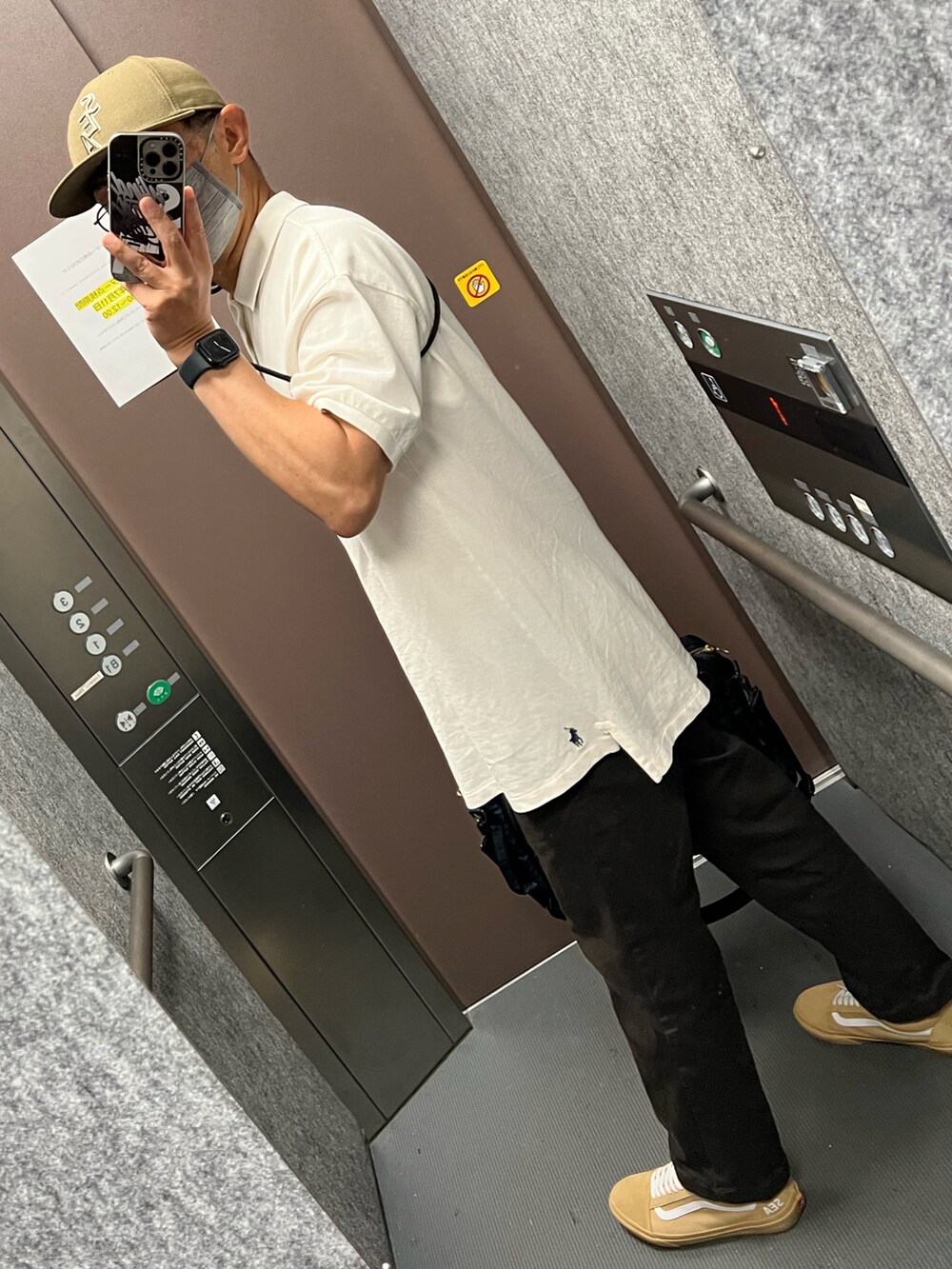 ホワイト系のポロシャツ、グレー系のチノパンツ、ブルー系のビジネスバッグを着用したメンズの夏コーディネートの2枚目の写真