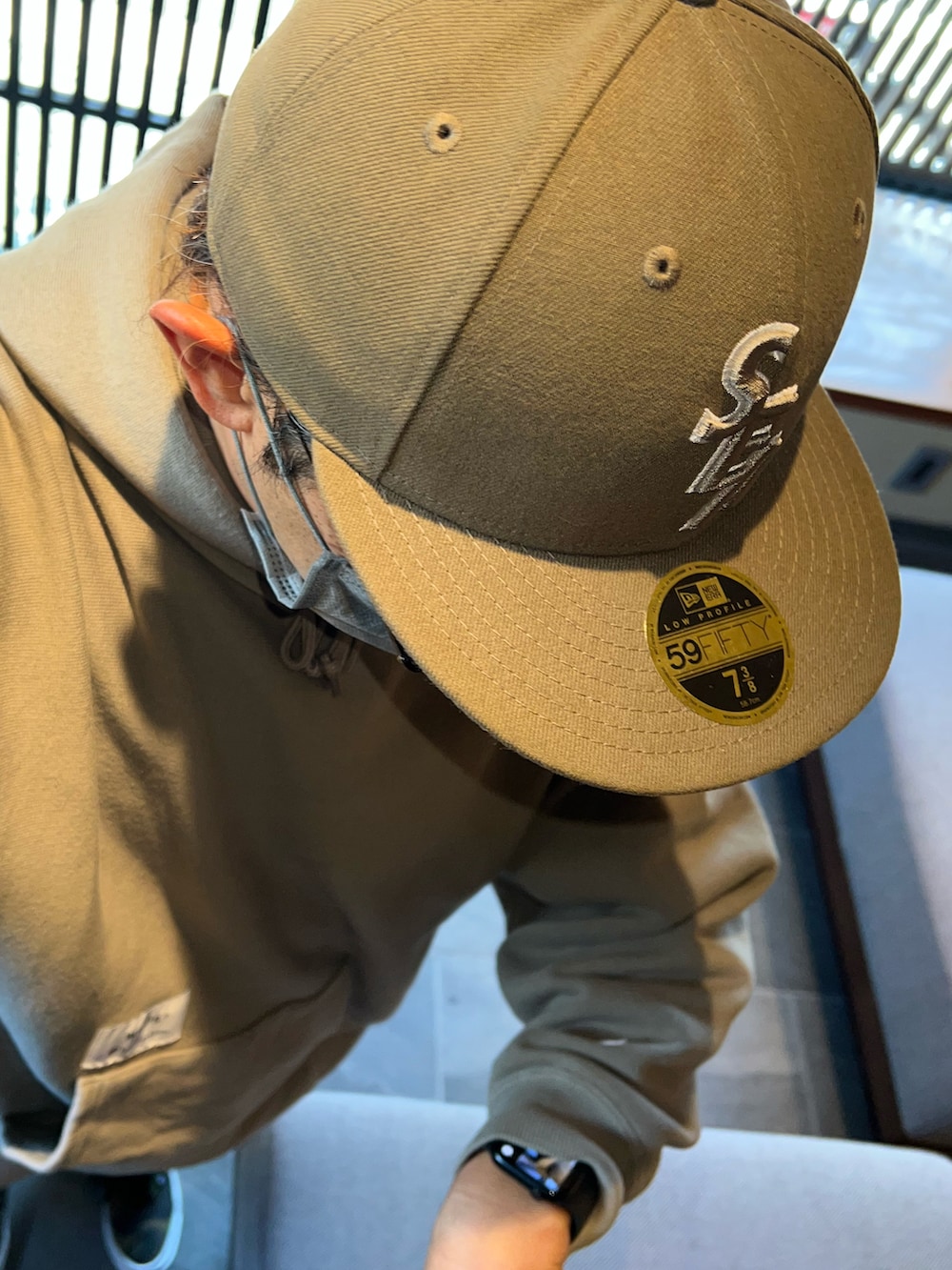 グリーン系のパーカー、ベージュ系のチノパンツ、グリーン系のスニーカーを着用したメンズの秋コーディネートの3枚目の写真