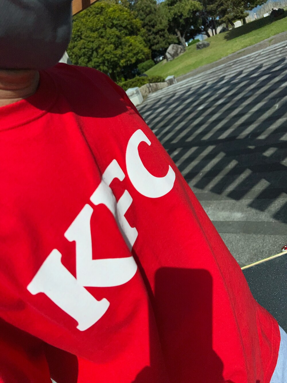 グレー系のスウェットパンツ、レッド系のTシャツ/カットソー、ベージュ系のスニーカーを着用したメンズの春コーディネートの3枚目の写真