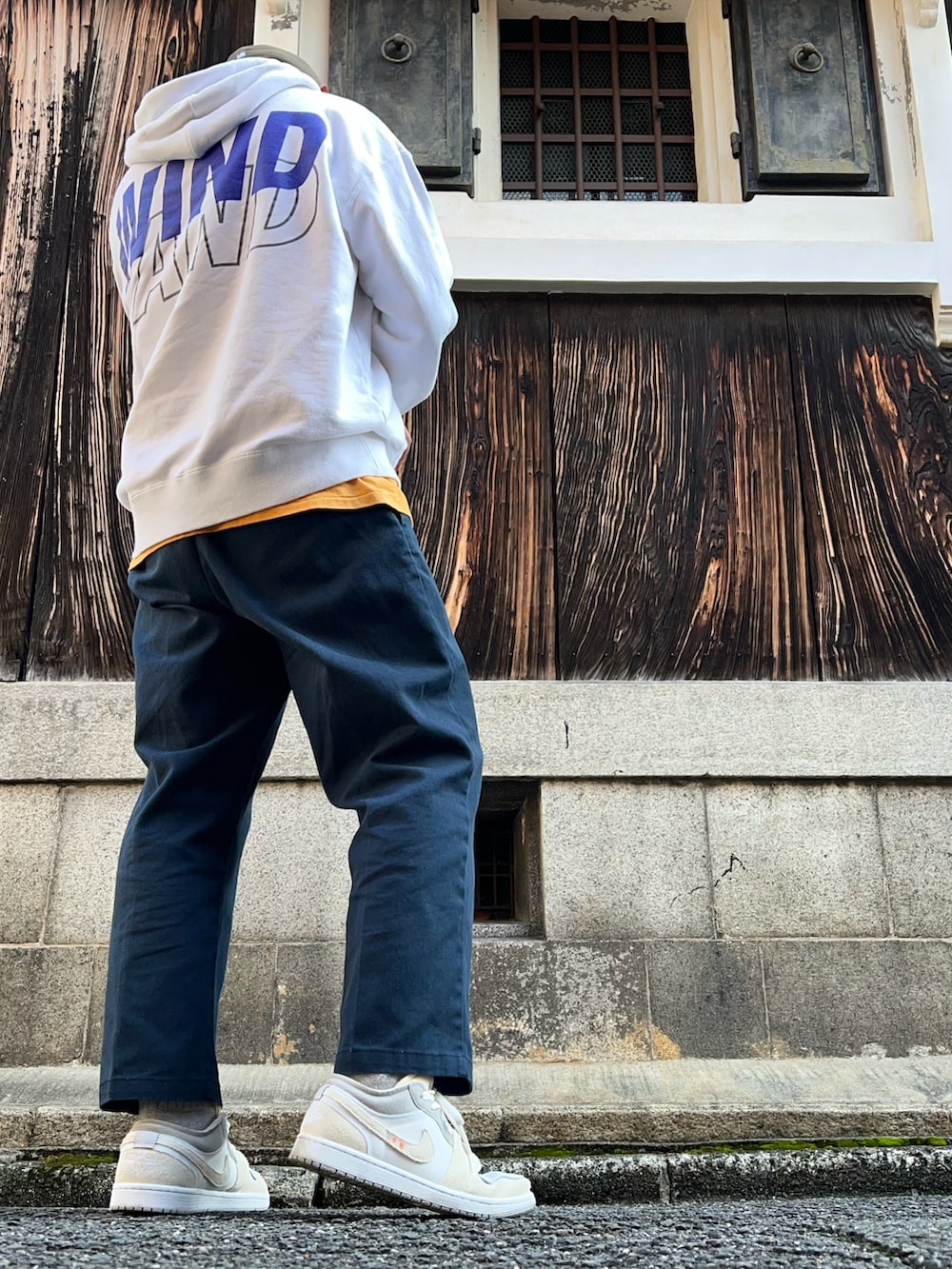 ブルー系のチノパンツ、オレンジ系のTシャツ/カットソー、ホワイト系のパーカーを着用したメンズの秋コーディネートの2枚目の写真