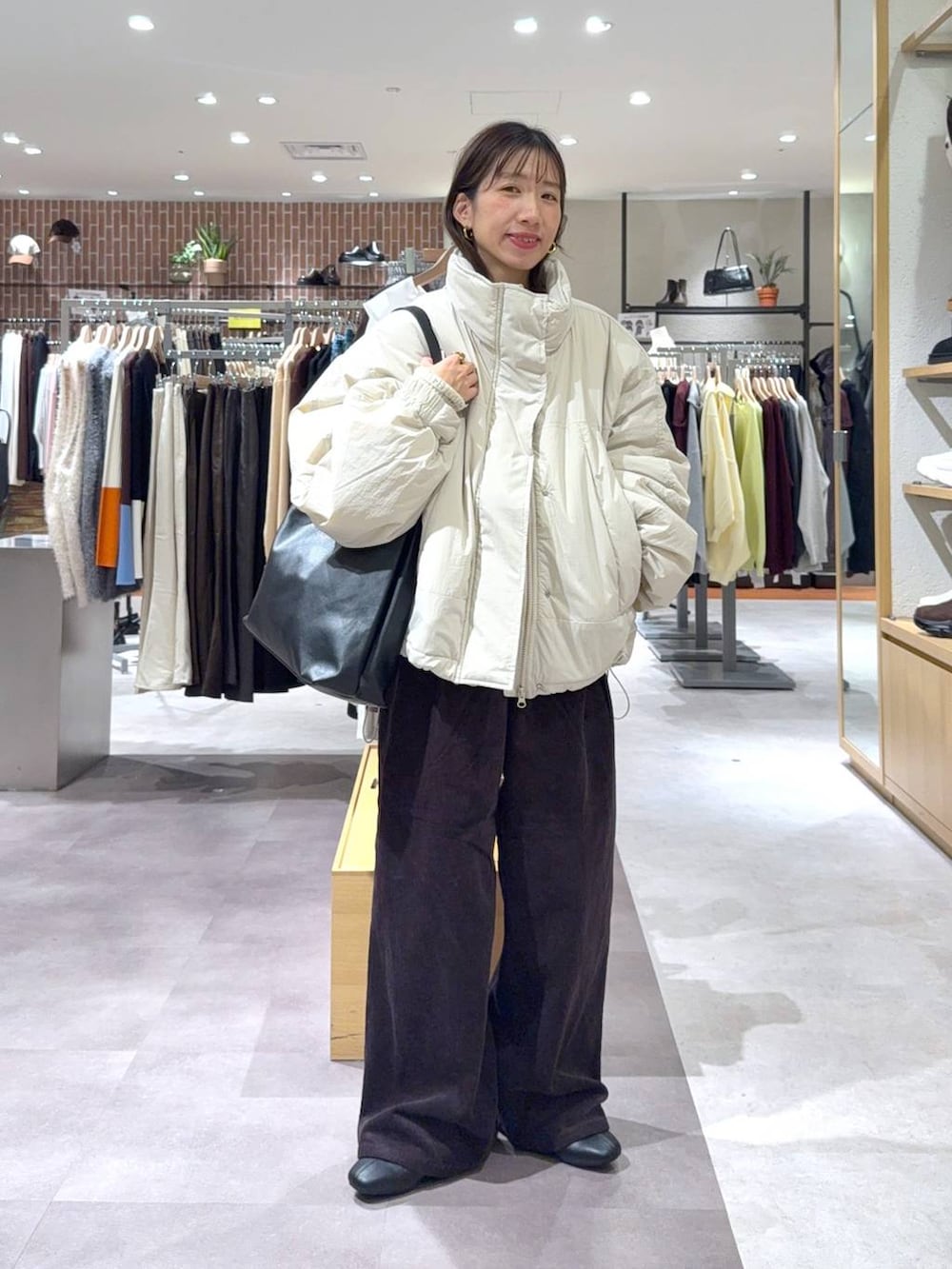 ブラック系のショルダーバッグ、ホワイト系のその他アウター、グレー系のその他パンツを着用したレディースの秋コーディネートの2枚目の写真