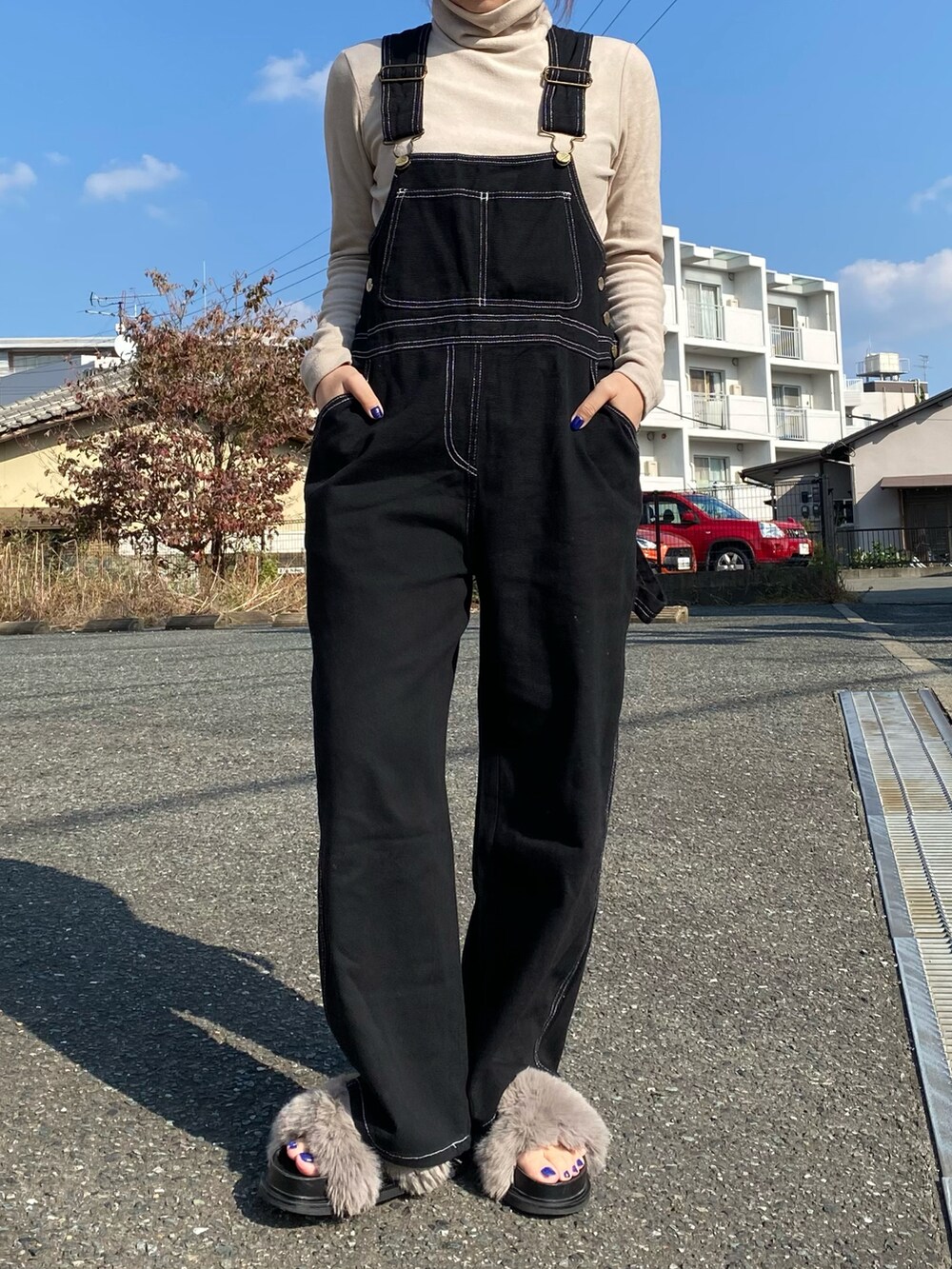 グレー系のシューズ、ブラック系のオールインワン・サロペット、ベージュ系のTシャツ/カットソーを着用したレディースの秋コーディネートの3枚目の写真