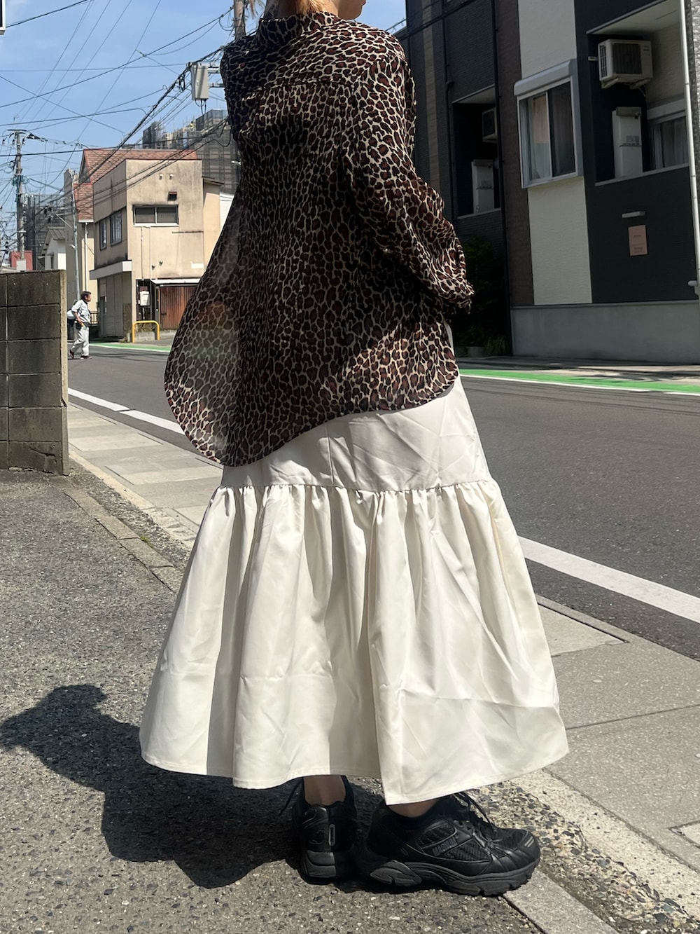 ホワイト系のジャンパースカート、ブラック系のシューズ、ブラウン系のトップスを着用したレディースの春コーディネートの2枚目の写真