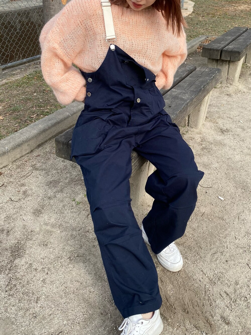 ホワイト系のスニーカー、ブルー系のオールインワン・サロペット、ピンク系のニット/セーターを着用したレディースの冬コーディネートの2枚目の写真