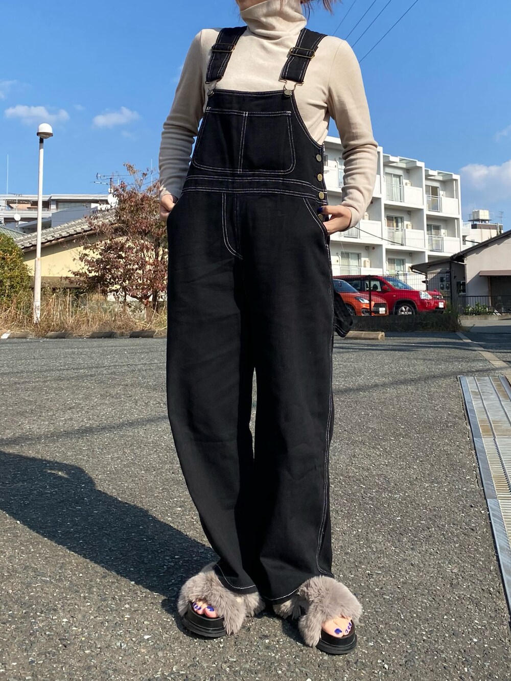 グレー系のシューズ、ブラック系のオールインワン・サロペット、ベージュ系のTシャツ/カットソーを着用したレディースの秋コーディネートの2枚目の写真