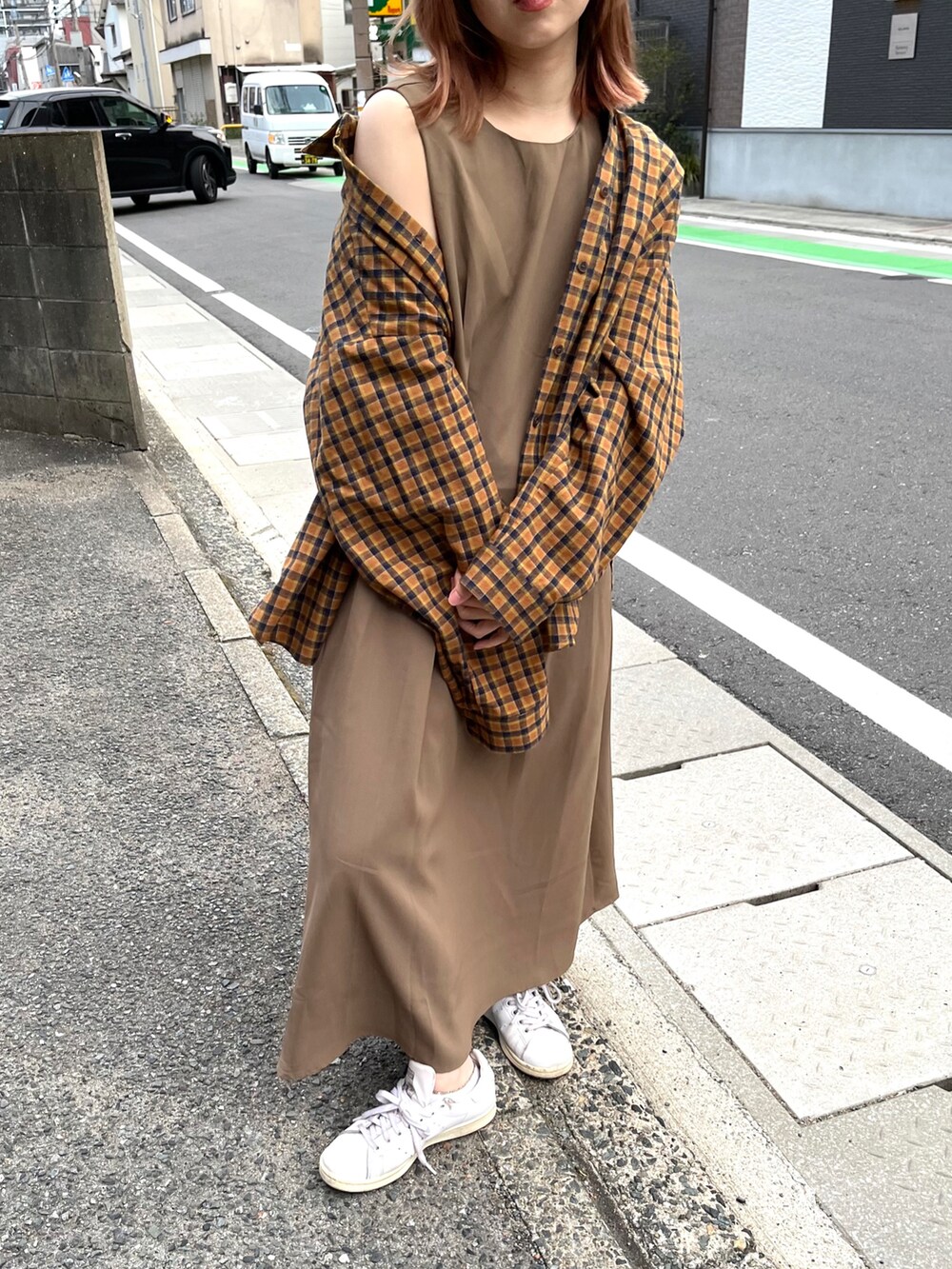 ホワイト系のスニーカー、グレー系のワンピース、ブラウン系のトップスを着用したレディースの春コーディネートの2枚目の写真