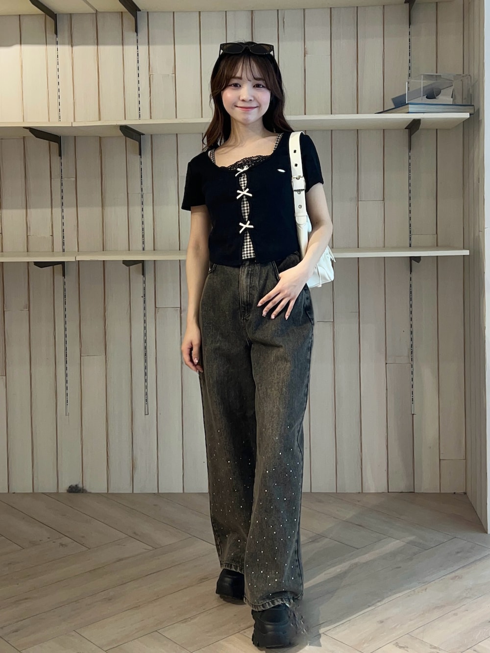 ブラック系のTシャツ/カットソー、ブラック系のデニムパンツ、ホワイト系のショルダーバッグを着用したレディースの春コーディネートの4枚目の写真