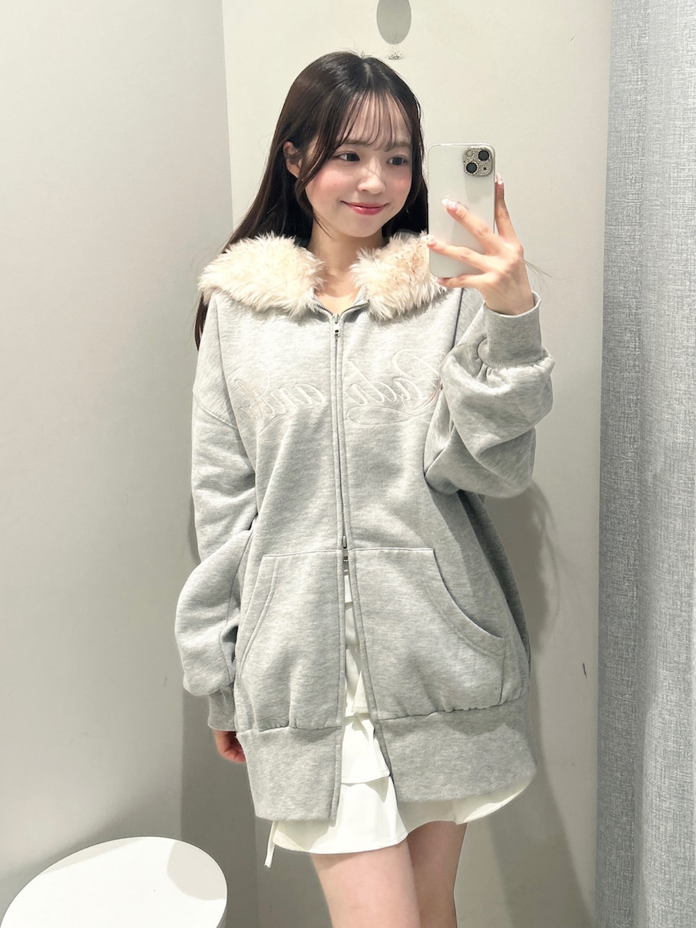 グレー系のパーカー、ホワイト系のスカートを着用したレディースの秋コーディネートの3枚目の写真