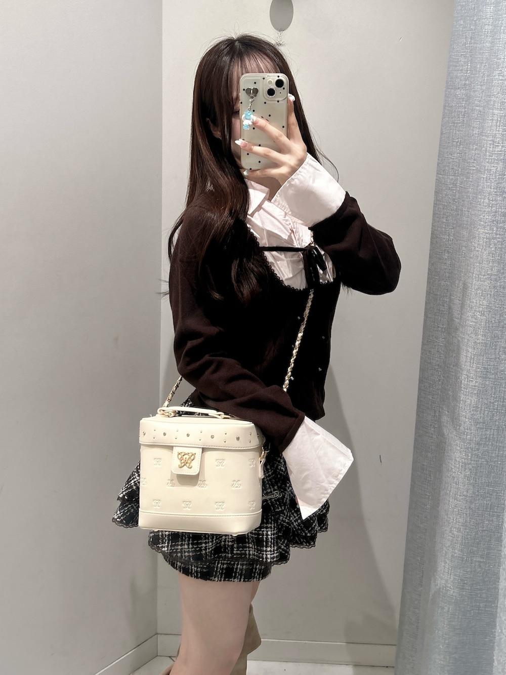 ブラウン系のニット/セーター、ブラウン系のスカート、ホワイト系のショルダーバッグを着用したレディースの秋コーディネートの4枚目の写真