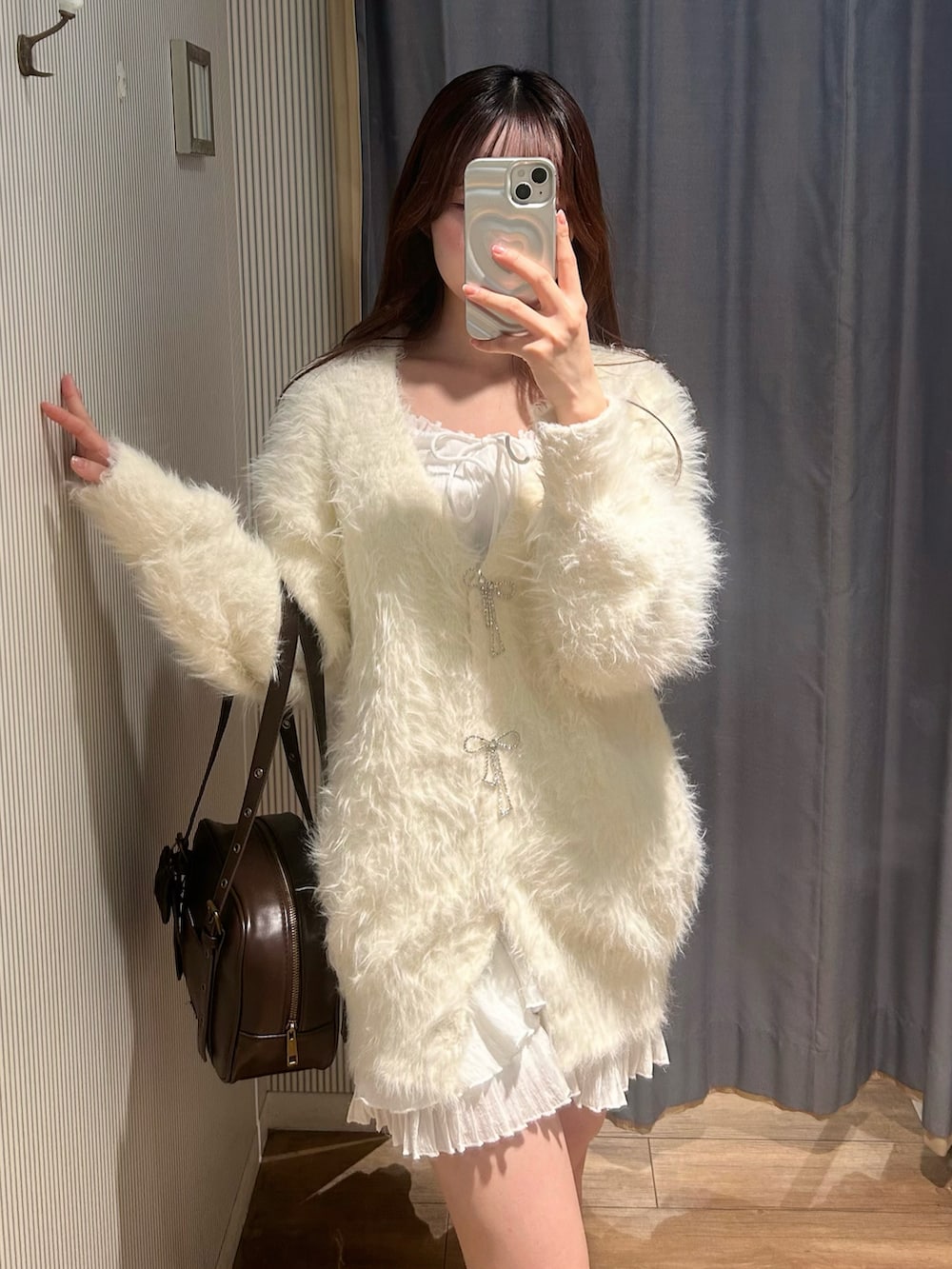 ブラウン系のショルダーバッグ、ホワイト系のカーディガン/ボレロ、ホワイト系のワンピースを着用したレディースの冬コーディネートの3枚目の写真