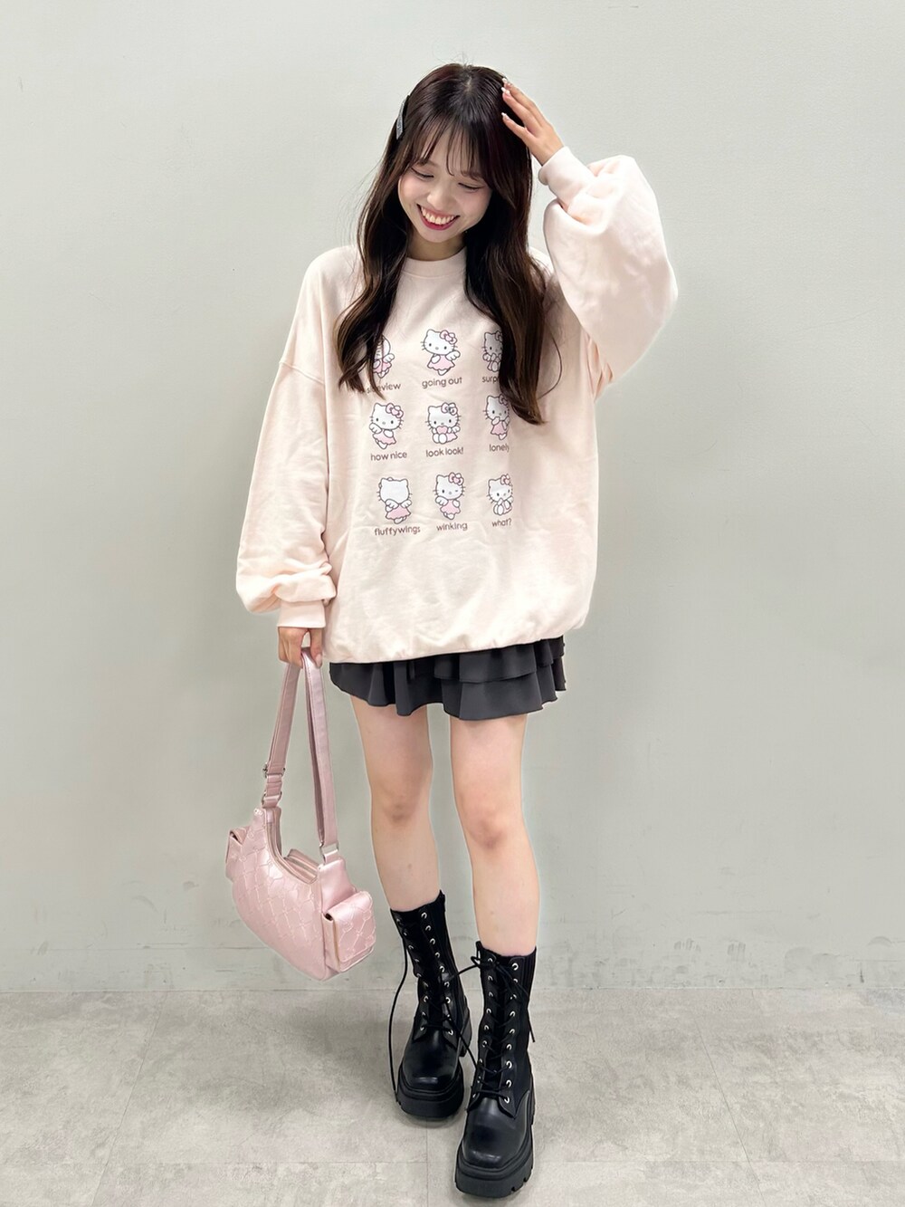 ピンク系のトップス、ピンク系のショルダーバッグ、グレー系のスカートを着用したレディースの秋コーディネートの2枚目の写真